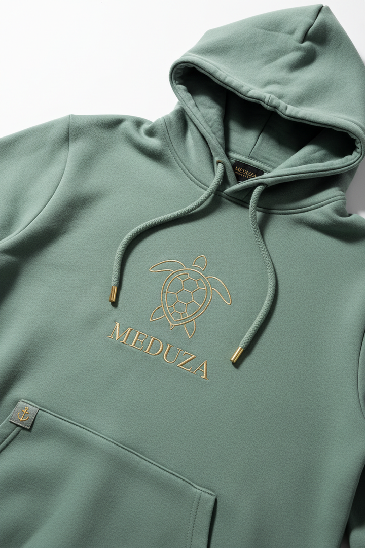 Sage green luxury hoodie with minimal gold sea turtle graphic and MEDUZA text
